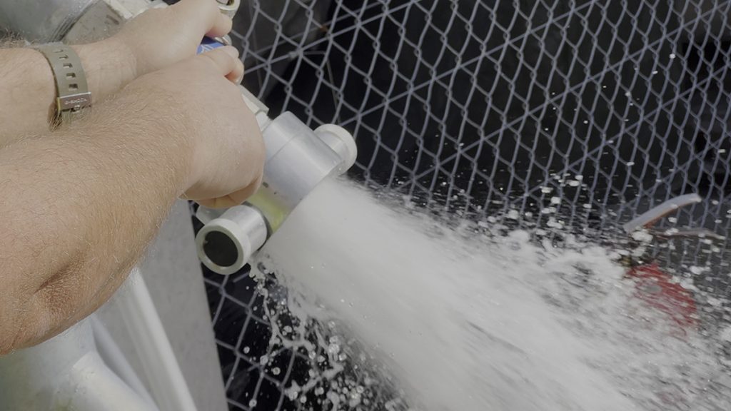 A close-up of a person testing the flow of a hydrant and water is pouring out
